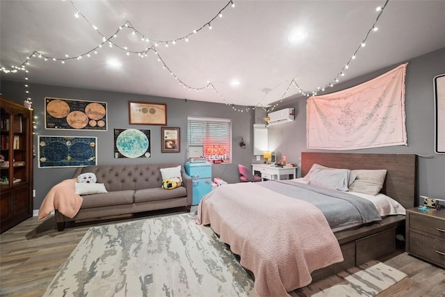 bedroom with a wall mounted AC, track lighting, and wood finished floors