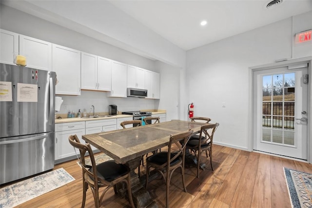 kitchen with light wood-type flooring, visible vents, stainless steel appliances, and a sink