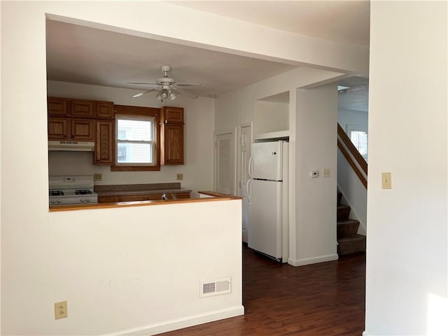 kitchen with visible vents, a ceiling fan, a peninsula, white appliances, and under cabinet range hood