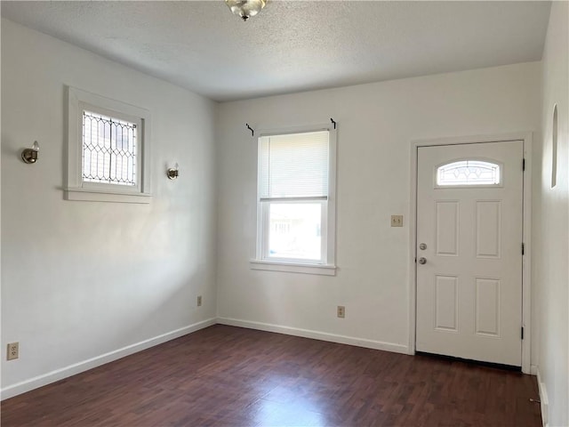 entrance foyer featuring a textured ceiling, baseboards, and dark wood-type flooring