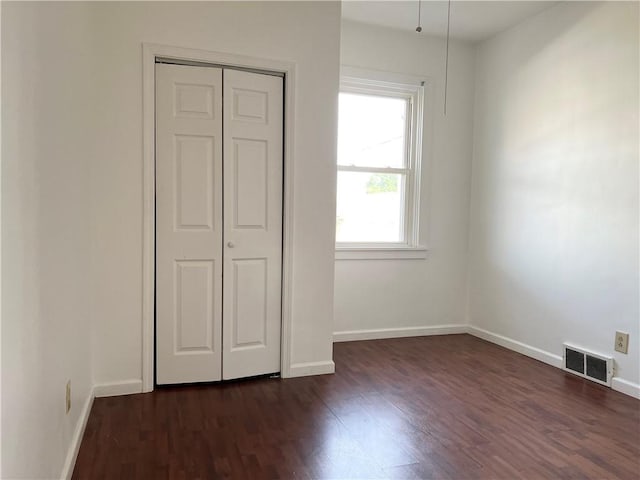 unfurnished bedroom featuring baseboards, visible vents, and dark wood-type flooring