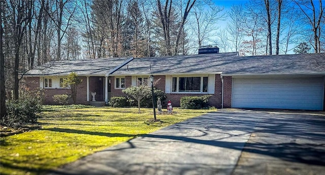 ranch-style house with driveway, a garage, a chimney, a front yard, and brick siding