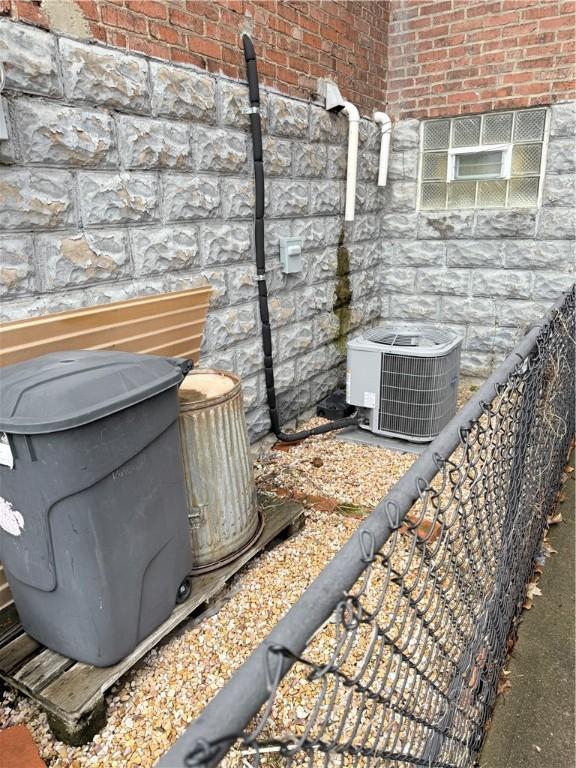 exterior details featuring brick siding, central AC unit, and a wood stove