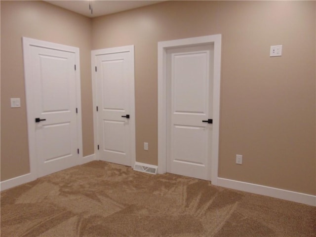 carpeted spare room with visible vents and baseboards