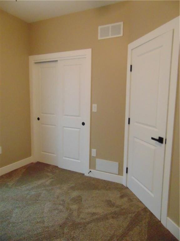 unfurnished bedroom with carpet floors, a closet, visible vents, and baseboards