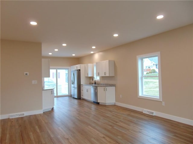 kitchen featuring white cabinetry, visible vents, stainless steel appliances, and a sink