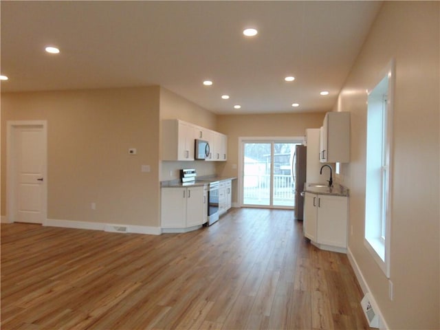 kitchen with appliances with stainless steel finishes, a sink, light wood-style flooring, and recessed lighting