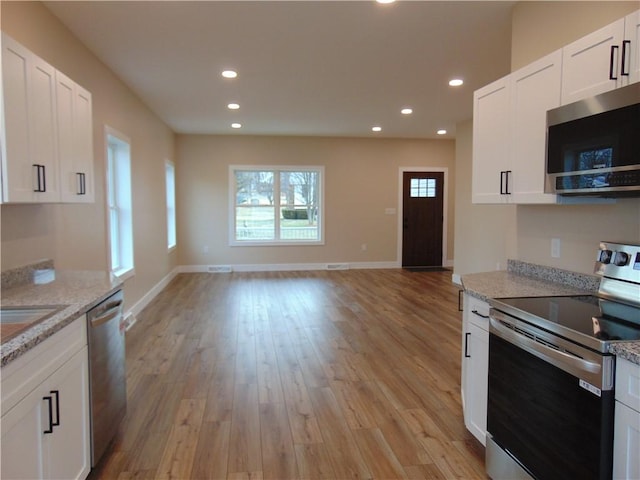 kitchen featuring light wood finished floors, appliances with stainless steel finishes, open floor plan, and recessed lighting