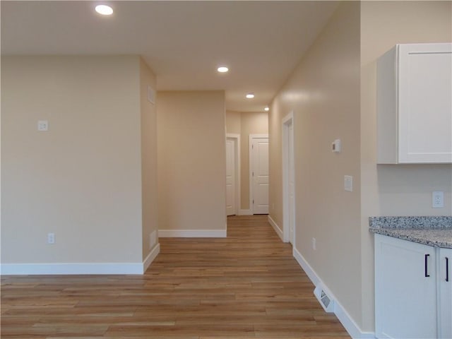 hall featuring baseboards, light wood-style floors, visible vents, and recessed lighting