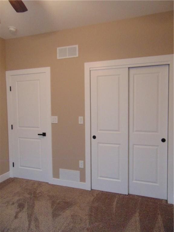 unfurnished bedroom with ceiling fan, carpet floors, visible vents, baseboards, and a closet