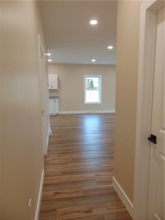 hallway with light wood-style flooring, baseboards, and recessed lighting