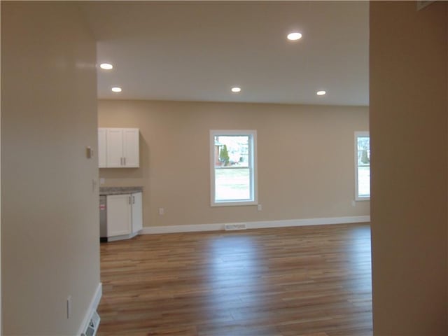 empty room featuring light wood-type flooring, visible vents, baseboards, and recessed lighting