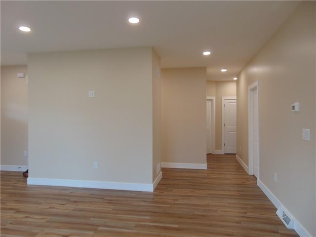 hallway with light wood-style floors, recessed lighting, visible vents, and baseboards