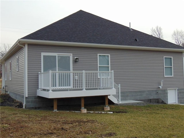 back of property with a shingled roof, a lawn, and a deck