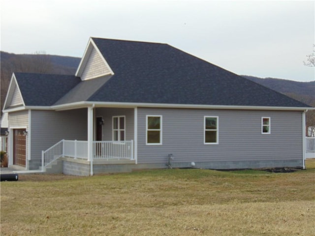 exterior space with a shingled roof, covered porch, a yard, and an attached garage