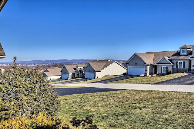 view of yard featuring aphalt driveway, a residential view, and an attached garage