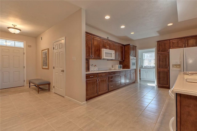 kitchen with dark brown cabinetry, white appliances, light countertops, and recessed lighting