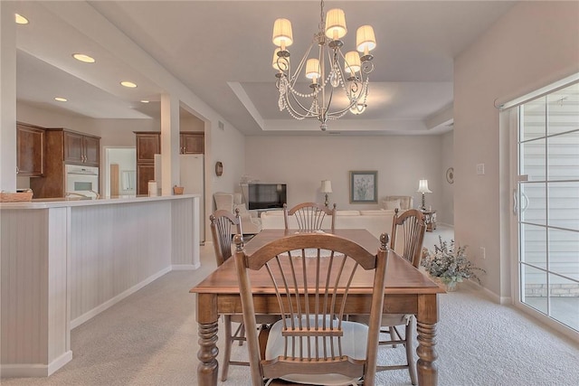 dining area featuring a tray ceiling, recessed lighting, light colored carpet, a chandelier, and baseboards