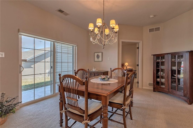 dining area featuring a chandelier, visible vents, and light colored carpet