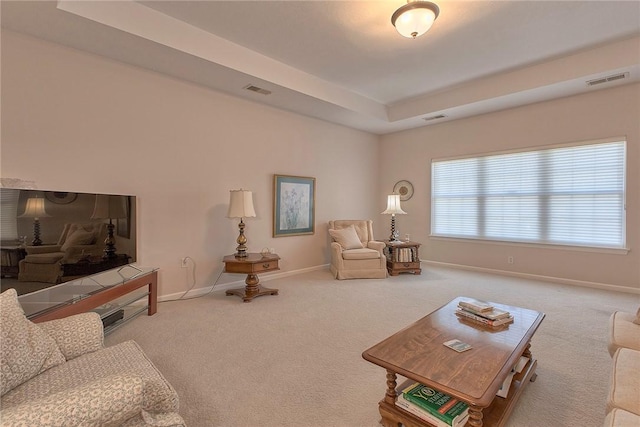 carpeted living area with a raised ceiling, visible vents, and baseboards