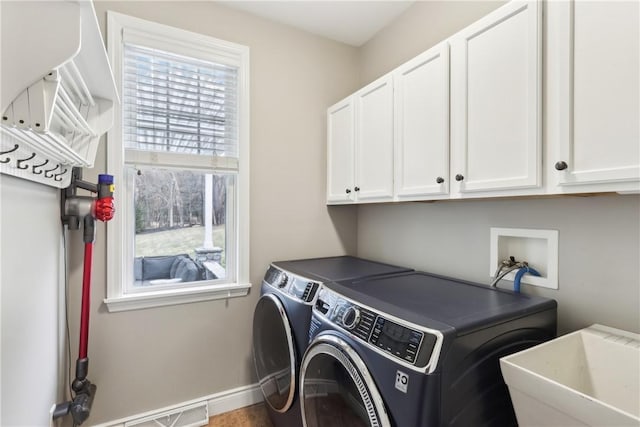 laundry room with cabinet space, baseboards, washer and dryer, and a sink