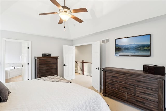 bedroom featuring lofted ceiling, visible vents, light colored carpet, a ceiling fan, and ensuite bath