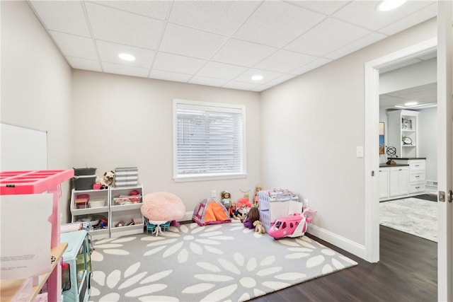 recreation room with a paneled ceiling, recessed lighting, baseboards, and wood finished floors