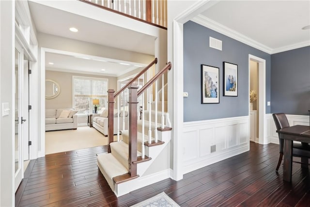 entryway featuring a wainscoted wall, crown molding, dark wood finished floors, visible vents, and stairway