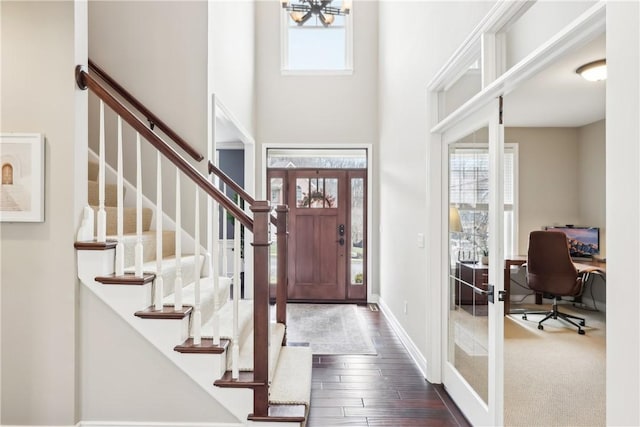 foyer entrance featuring dark wood-style flooring, plenty of natural light, and a towering ceiling