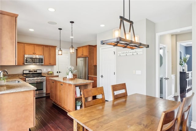 kitchen with appliances with stainless steel finishes, dark wood-type flooring, a center island, open shelves, and a sink