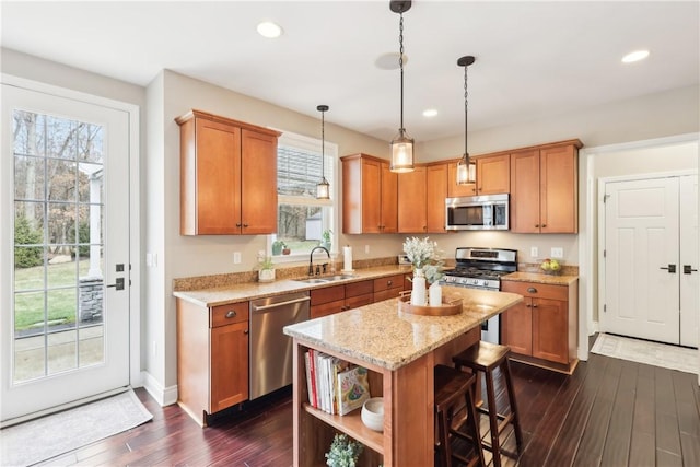 kitchen with a breakfast bar area, recessed lighting, stainless steel appliances, a sink, and dark wood finished floors