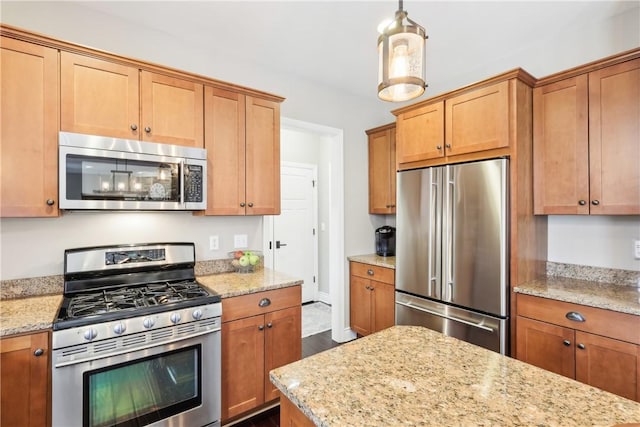 kitchen with light stone countertops, brown cabinetry, and stainless steel appliances