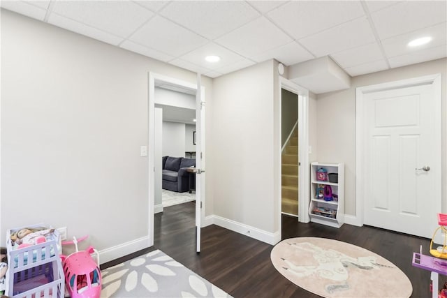 recreation room with a paneled ceiling, baseboards, dark wood finished floors, and recessed lighting