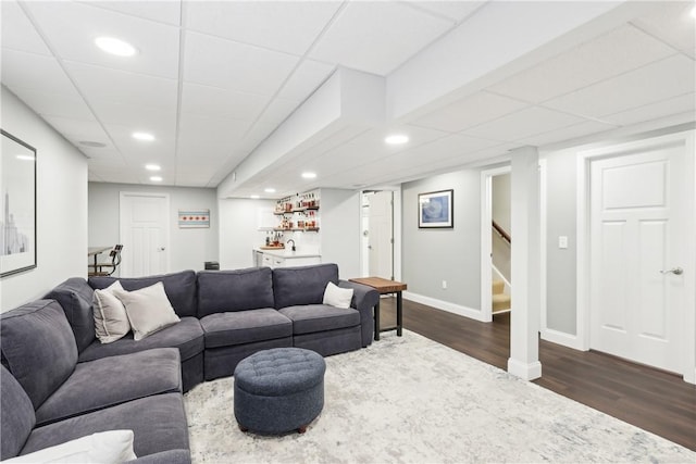 living room featuring dark wood-style floors, indoor wet bar, recessed lighting, baseboards, and stairs