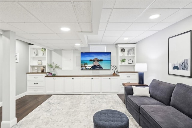 living area with recessed lighting, dark wood-style flooring, a drop ceiling, and baseboards