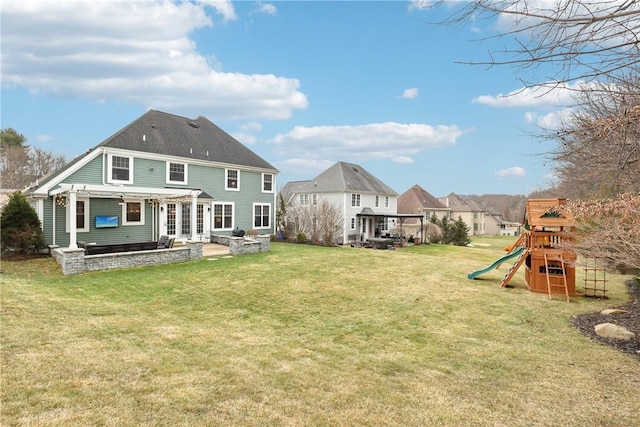 rear view of property featuring a pergola, a playground, a patio, and a lawn