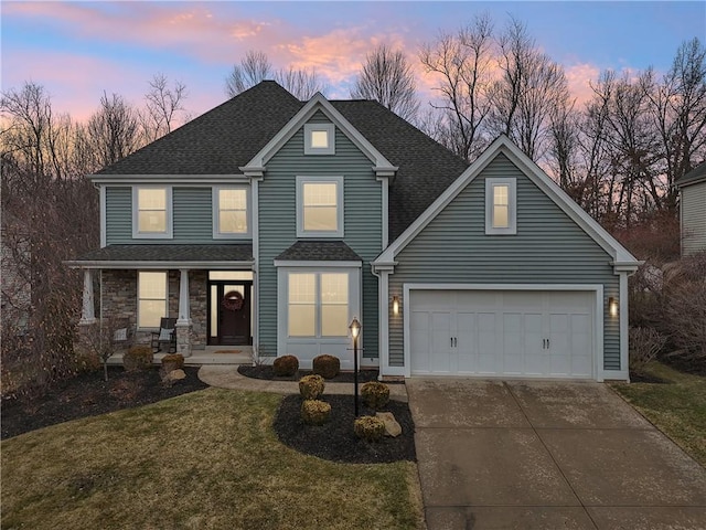 traditional-style home featuring driveway, a garage, a lawn, roof with shingles, and covered porch