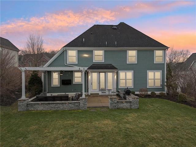 back of property featuring a patio area, a shingled roof, and a lawn