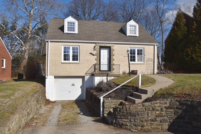 new england style home featuring a garage, brick siding, driveway, and a shingled roof