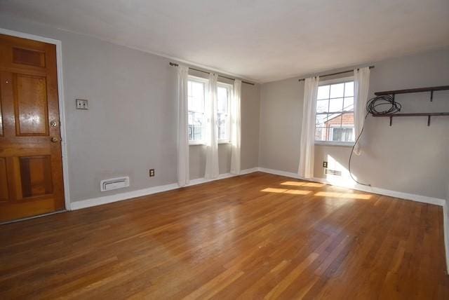 unfurnished living room with visible vents, baseboards, and wood finished floors