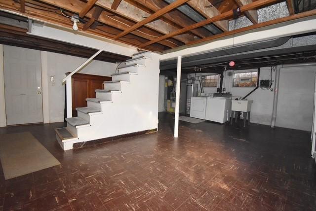 basement featuring washing machine and dryer, stairs, and a sink