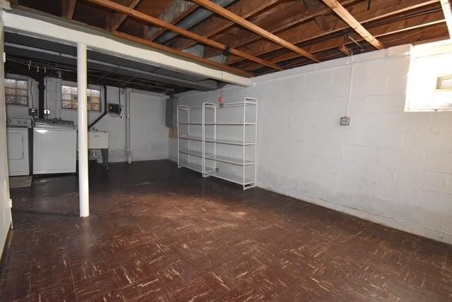 unfinished below grade area with a sink, dark floors, and washing machine and dryer