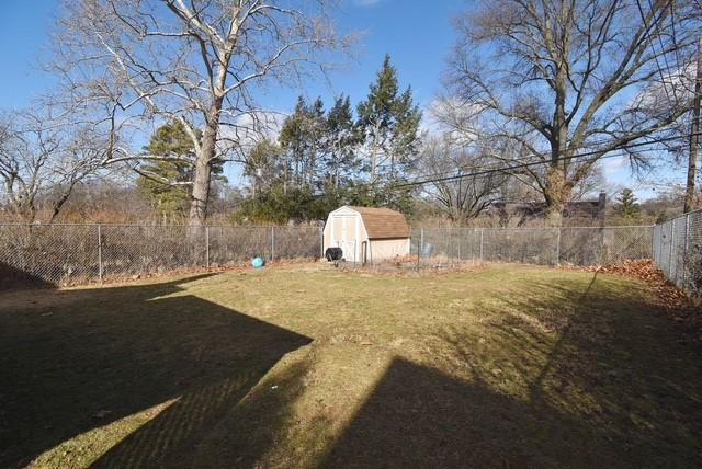 view of yard with a shed, a fenced backyard, and an outdoor structure