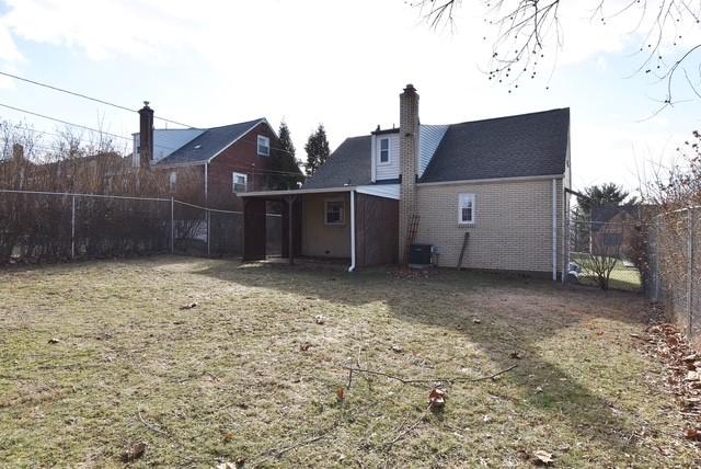 rear view of house featuring brick siding, a chimney, central air condition unit, a lawn, and a fenced backyard