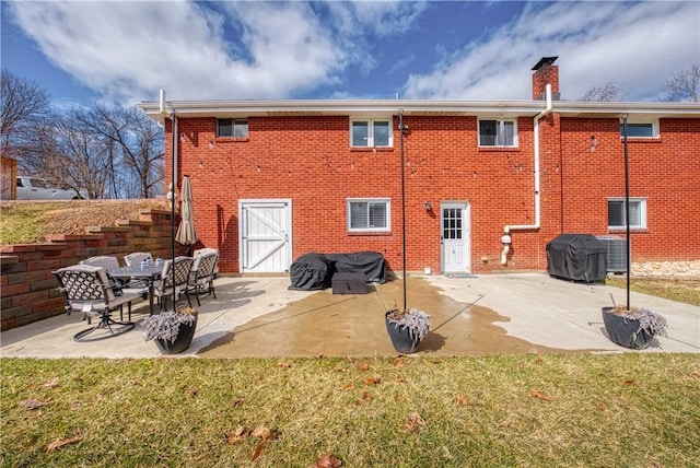 back of property featuring central AC unit, brick siding, and a patio area