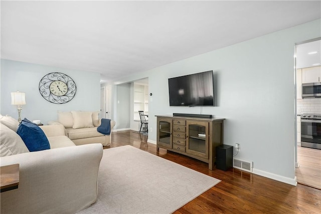 living area with visible vents, baseboards, and wood finished floors