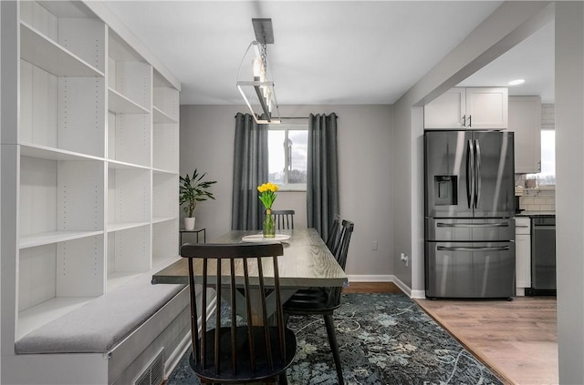 dining area with baseboards, visible vents, and light wood-style floors