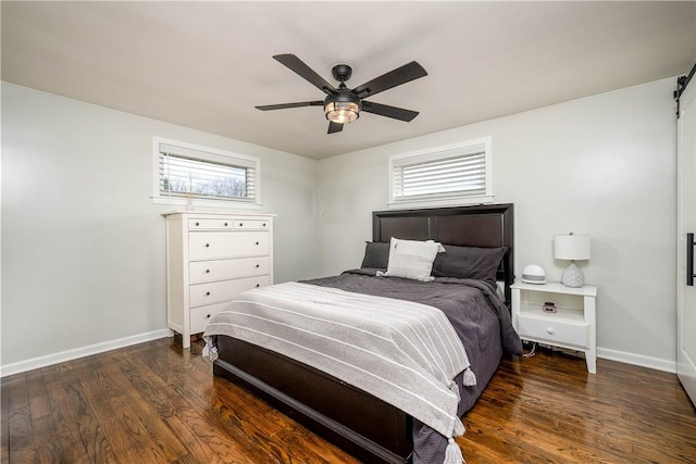 bedroom with ceiling fan, baseboards, wood finished floors, and a barn door