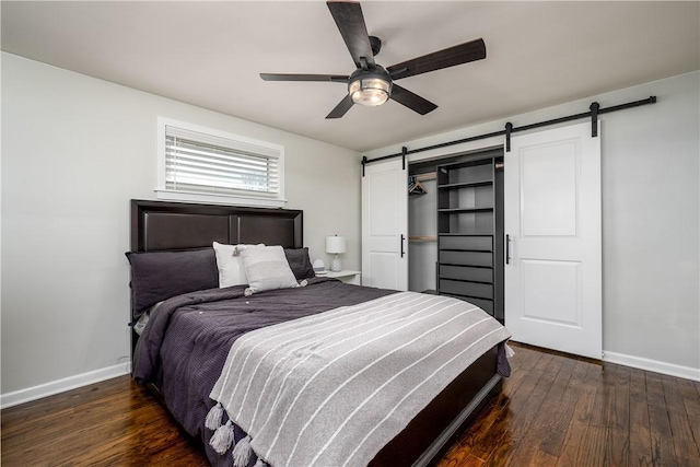 bedroom with a ceiling fan, baseboards, hardwood / wood-style floors, and a barn door