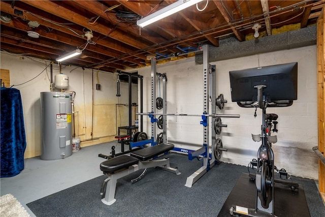 exercise room featuring water heater and concrete block wall